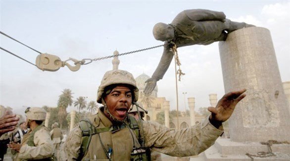 عناصر من القوات الأمريكية بالقرب من تمثال مهدم لصدام حسين (غيتي)