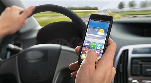 سائق يستعمل هاتفه المحمول أثناء قيادة سيارته (أرشيف)