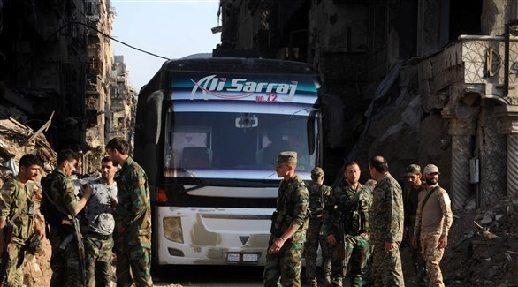 عناصر من الجيش السوري بجانب باصات لنقل مسلحين مع عائلاتهم  (أرشيف)