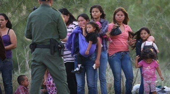 شرطي أمريكي أمام مهاجرين مكسيكيين يحاولون دخول الولايات المتحدة (أرشيف)