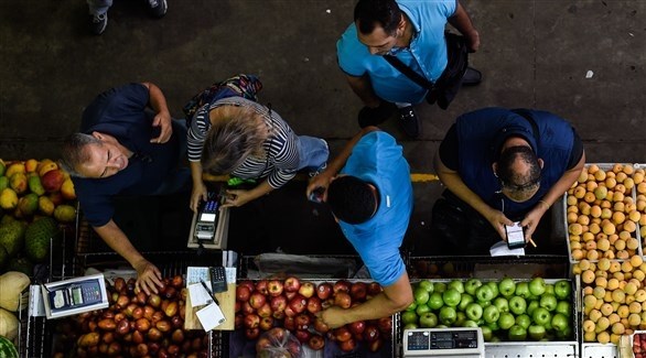 أشخاص يبتاعون البقالة في أحد الأسواق في فنزويلا (أ ف ب)