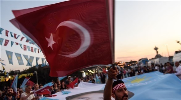 تركي يرفع علم بلاده خلال إحدى التجمعات الانتخابية (أ ف ب)