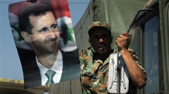 جندي يحمل صورة الرئيس بشار الأسد (أرشيف/ غيتي)