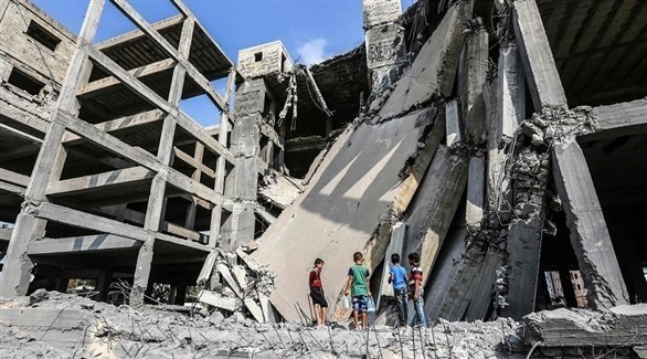 أطفال يقفون أمام مبنى مدمر في غزة (أرشيف)