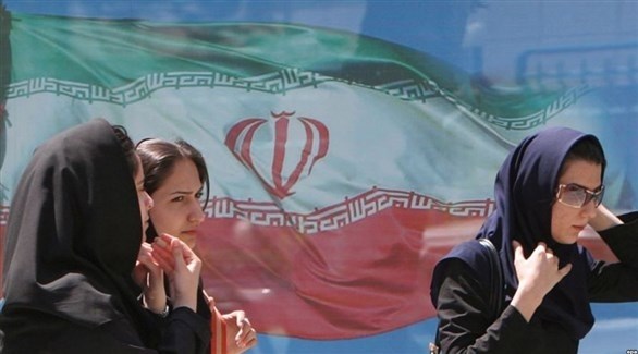 نساء تمر بالقرب من صورة لعلم إيراني (أرشيف)