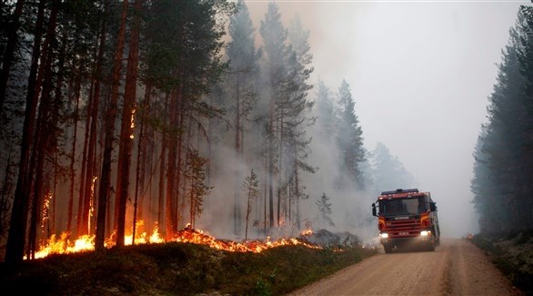 سيارة اطفاء تمر بجانب حريق السويد (أ ف ب)