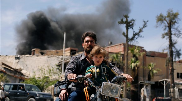 رجل يفر مع طفلته من مدينة دوما في دمشق ، سوريا