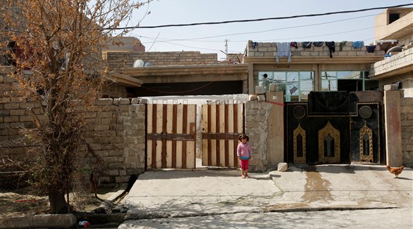 طفلة عراقية فر جميع أفراد أسرتها، تقف أمام منزلها في الموصل
