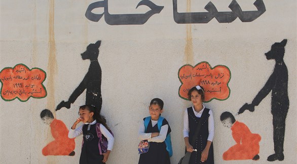 طالبات عراقيات أمام غرافيتي يظهر جرائم داعش في الموصل