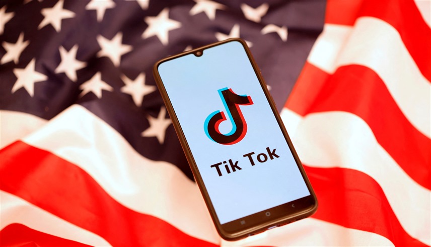  شعار تيك توك على الهاتف الذكي والعلم الأمريكي (رويترز)