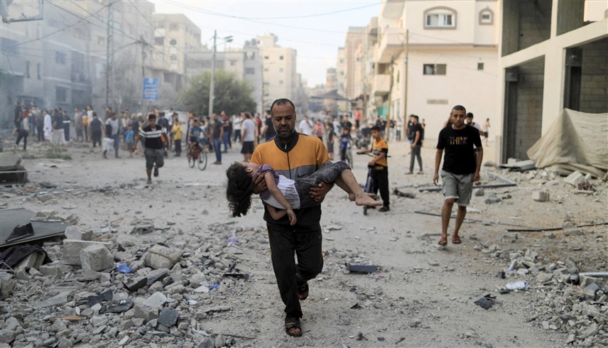 فلسطيني يسعف طفلة أصيبت بقصف إسرائيلي على غزة (رويترز)