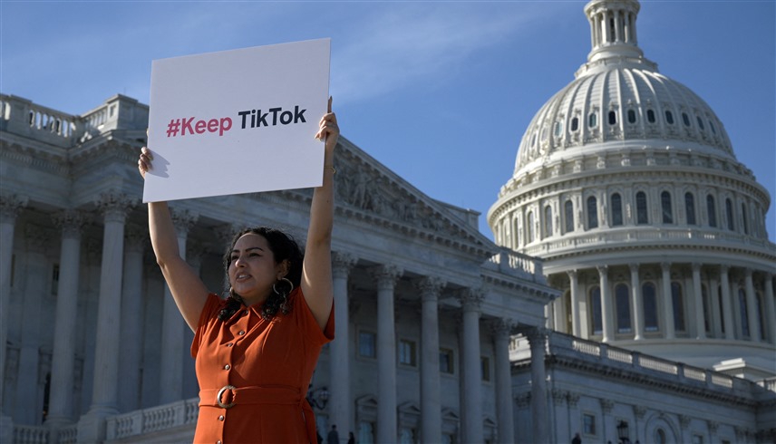 أمريكية تتظاهر خارج مبنى الكونغرس الأمريكي رفضاً لحظر تيك توك (رويترز)