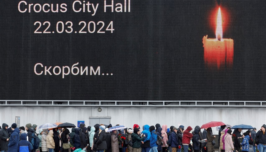 روس أمام شاشة مضاءة بشمعة تخليدا لذكرى هجوم موسكو (وكالات)