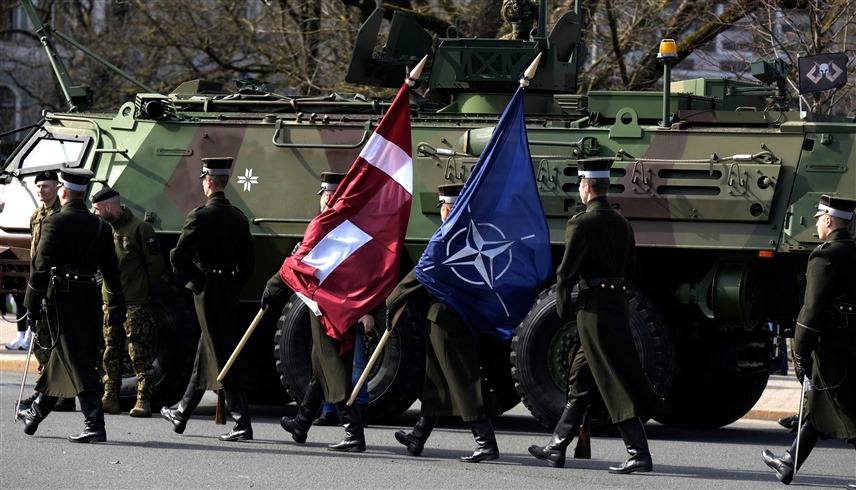 جنود لاتفيون يحملون راية الناتو وعلم بلادهم في ذكرى انضمام بلادهم للحلف (أرشيف)