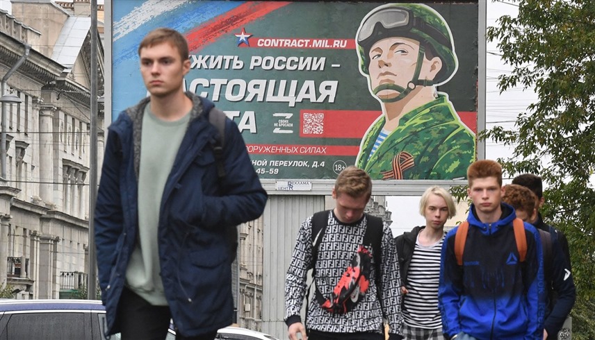 روس يسيرون أمام دعاية للخدمة العسكرية في سان بطرسبرغ (أرشيف)