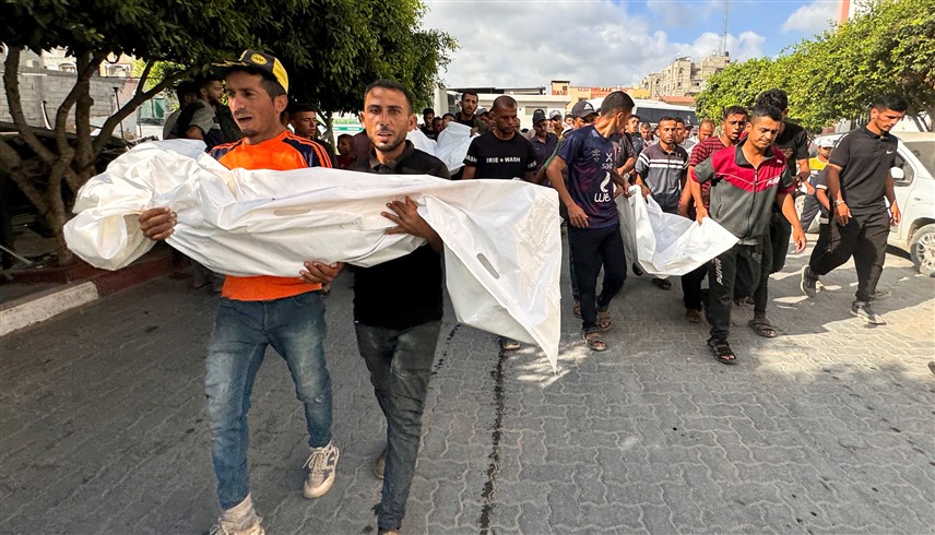 فلسطينيان يحملان جثمان قتيل في هجمات إسرائيلية على غزة (أرشيف)
