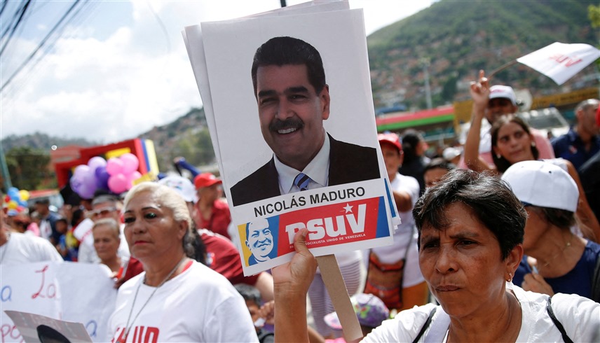 فنزويلية ترفع صورة لرئيس البلاد نيكولاس مادورو (رويترز)