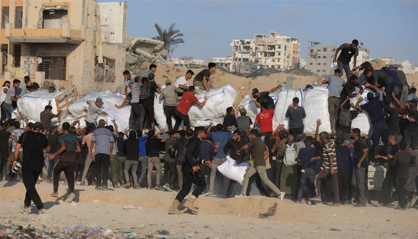 جموع من الفلسطينيين يتسابقون للحصول على المساعدات (رويترز)