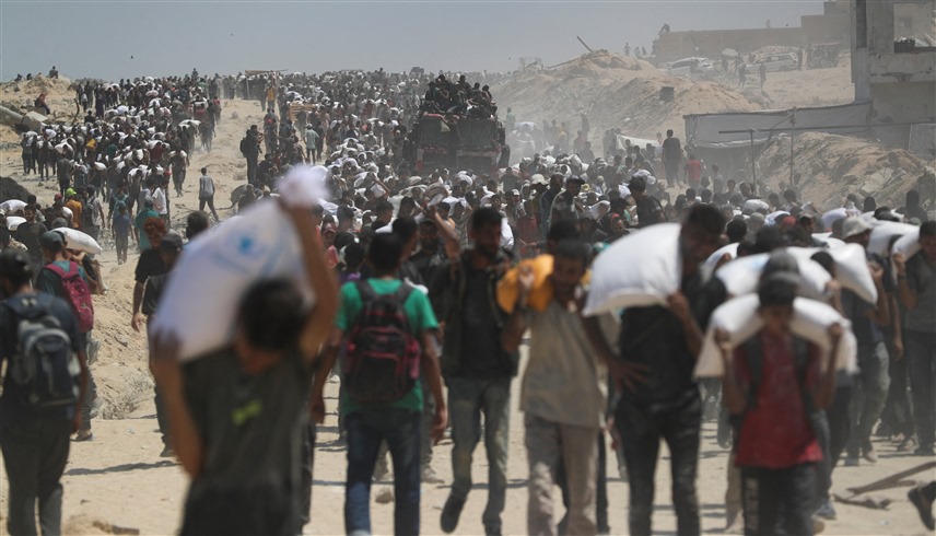 حشود من الفلسطينيين في غزة خلال رحلة شاقة للحصول على المساعدات (رويترز)