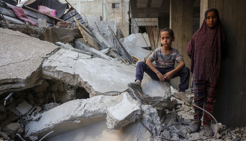 طفلان فلسطينيان يجلسان على أنقاض منزلهما في غزة (أ ف ب)