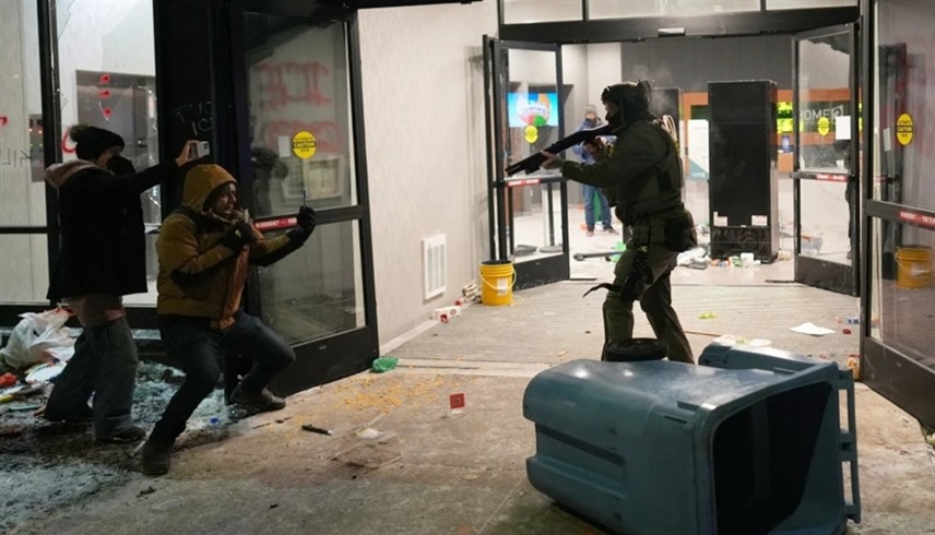 عميل من إدارة الهجرة يصوب سلاحه نحو مهاجر في مينيسوتا فيما يصور محتج الواقعة بهاتفه المحمول (أ ب)