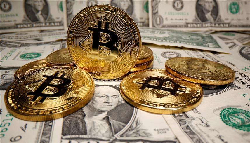 قطع معدنية تحمل شعار بيتكوين مع أوراق نقدية من فئة الدولار الأمريكي (رويترز)