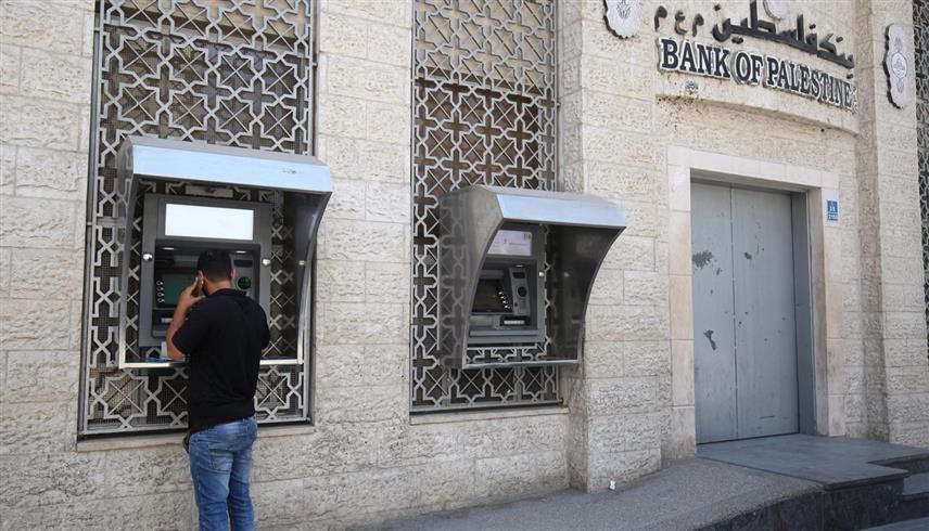 فلسطيني أمام جهاز صراف آلي (أ.ف.ب)