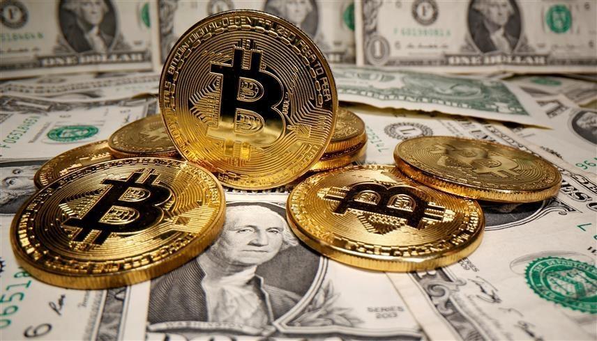 شعار عملة بيتكوين الرقمية مع أوراق نقدية من فئة الدولار (رويترز)