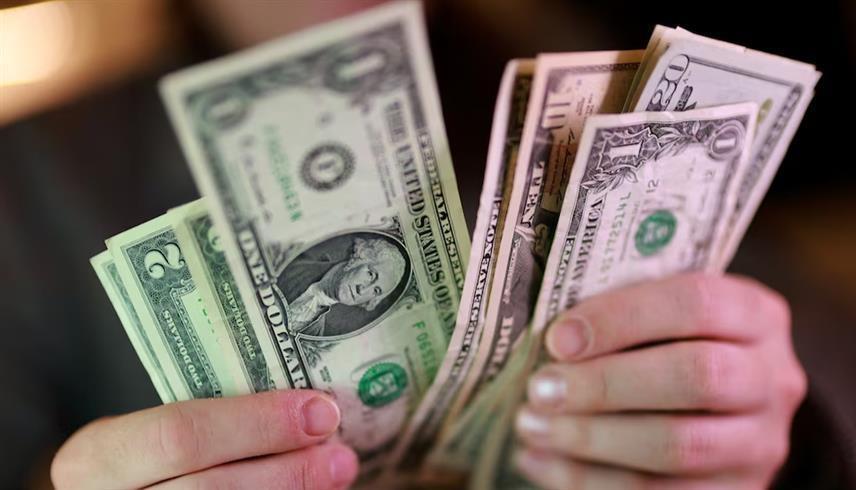 شخص يحمل أوراقاً نقدية من فئة الدولار الأمريكي في صورة توضيحية من (رويترز)