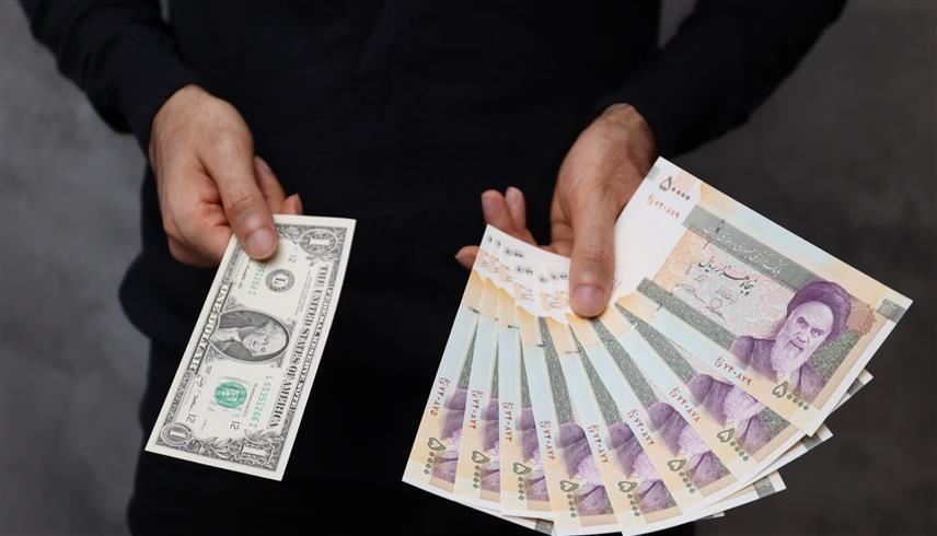 ريالات إيرانية وورقة نقدية من الدولار الأمريكي (رويترز)