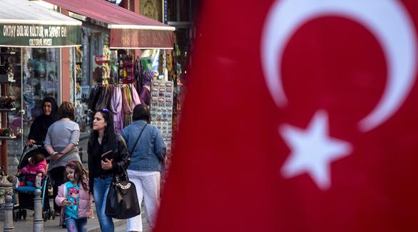 سكان إحدى المدن التركية يمرون بالقرب من العلم (أرشيف)