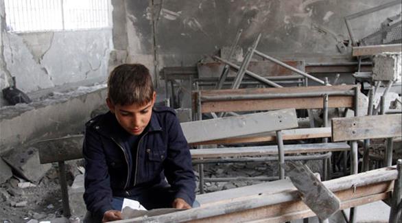 طفل سوري يجلس في مدرسته وسط الركام (أرشيف)