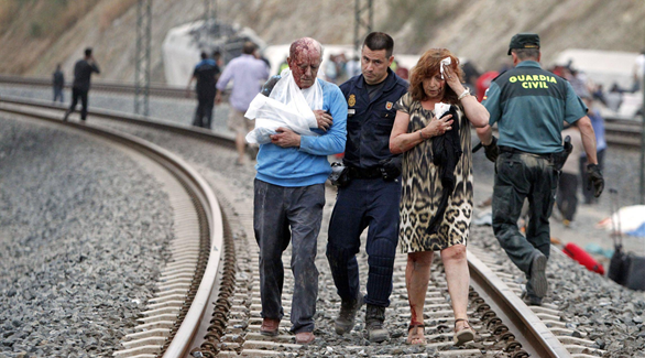 شرطي إسباني يسعف اثنين من جرحى حادث قطار سانتياغو دي كومبوستيلا (رويترز)
