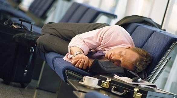 مسافر ينام على مقعد في أحد المطارات عد رحلة طويلة (ديلي ميل)