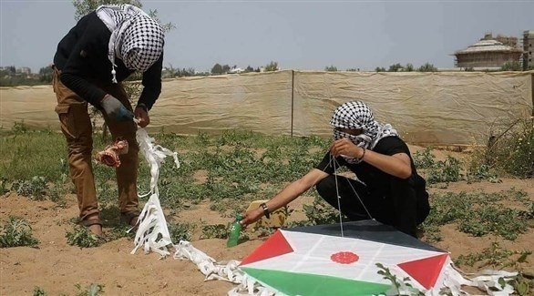 فلسطينيان يحضران طائرة ورقية بقنابل حارقة(أرشيف)