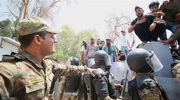 عناصر من الأمن العراقي أمام محتجين في حقل الزبير النفطي (رويترز)