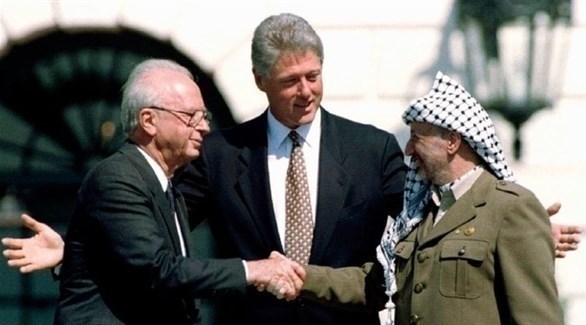 المصافحة التاريخية بين الزعيم الفلسطيني ياسر عرفات ورئيس الوزراء الغسرائيلي اسحق رابين، وبينهما الرئيس الأمريكي بيل كلينتون خلال مراسم توفيع اتفاقات أوسلو.(أرشيف)