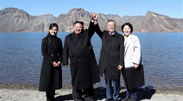 زعيم كوريا الجنوبية ممسكاً بيد زعيم كوريا الشمالية (رويترز)