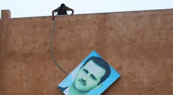 مقاتل يسقط صورة الرئيس السوري بشار الأسد في إدلي عام 2015.(أرشيف)