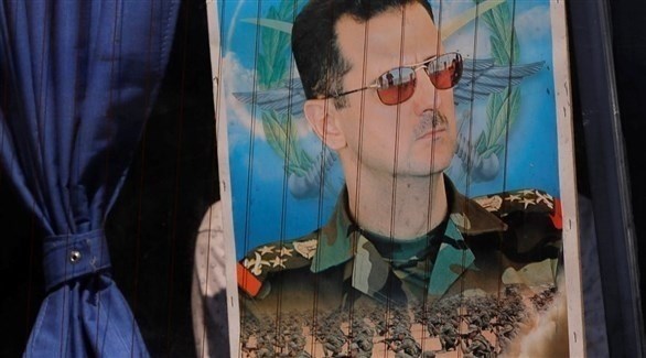 لاجئ سوري يرفع صورة للرئيس بشار الأسد في حافلة متجهة إلى بشار الأسد.(أرشسف)