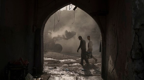 عمال بناء يرفعون أنقاض متاجر مدمرة في الموصل.(أرشيف)