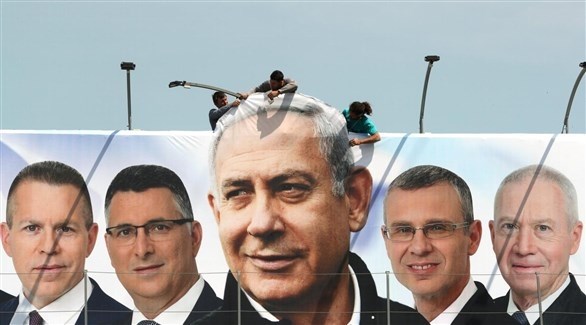 عمال يعلقون لوحةعليها صورة رئيس الوزراء الإسرائيلي بنيامين نتانياهو ومرشحين من الليكود.(أرشيف)