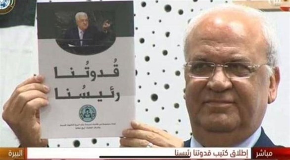 القيادي الفلسطيني صائب عريقات يحمل كتاب "قدوتنا رئيسنا" (أرشيف)