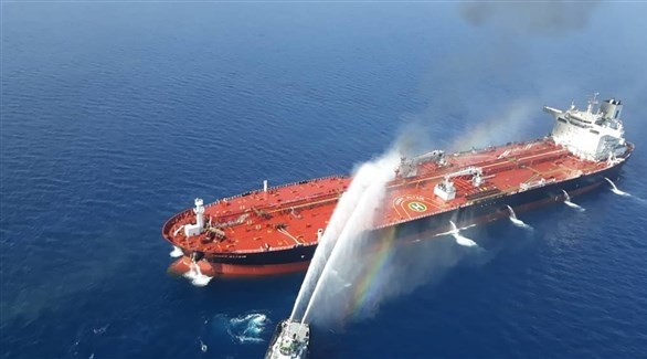 سفينة تطفئ الحريق في ناقلة النفط التي تعرضت لهجوم في بحر عمان أمس (أ ف ب)