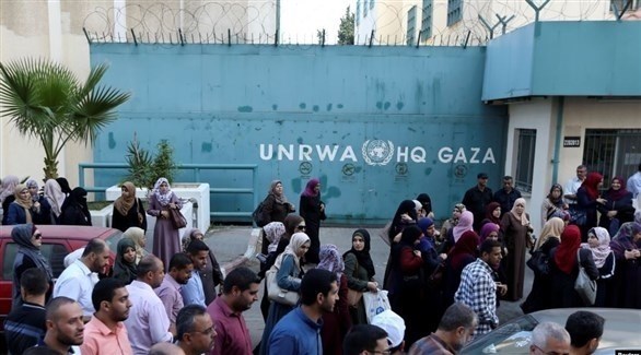 نساء ورجال من غزة يقفون أمام بوابة مدرسة للأونروا (أرشيف)