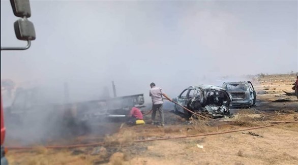 ليبيون يطفئون سيارات مشتعلة جراء هجوم إرهابي على مقبرة الهواري (تويتر)