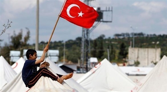 فنى سوري يحمل علم تركيا في مخيم للاجئين.(أرشيف)