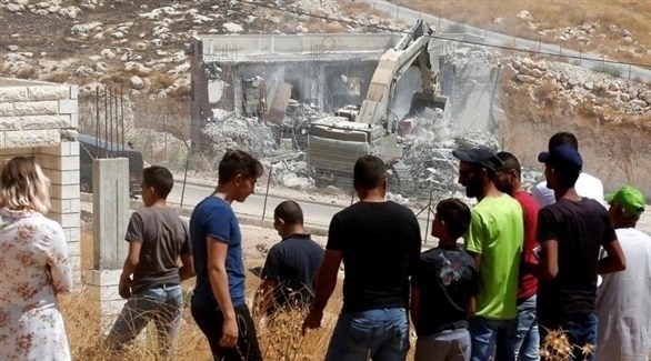 شباب يراقبون هدم  منازل الفلسطينيين (رويترز)