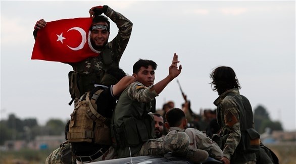 عناصر مسلحة تحمل العلم التركي على متن آليات متجهة إلى الحدود مع سوريا (رويترز)