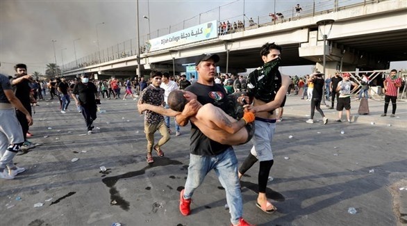 عراقي ينقل مصاباً في المظاهرات لمحاولة إسعافه (أرشيف)